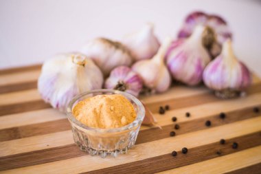 Kahverengi ahşap bir tahtanın üzerinde biber ve sarımsak çeşnili güzel ve büyük bir sarımsak var..