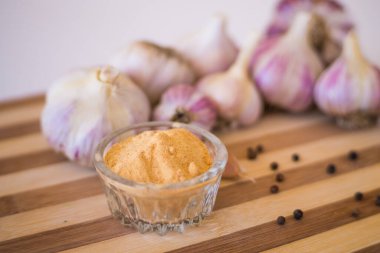 Kahverengi ahşap bir tahtanın üzerinde biber ve sarımsak çeşnili güzel ve büyük bir sarımsak var..