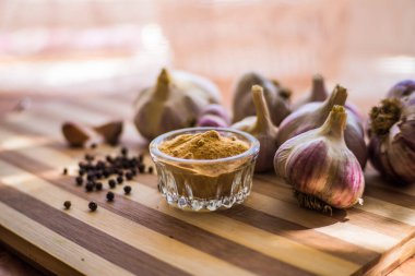 Kahverengi ahşap bir tahtanın üzerinde biber ve sarımsak çeşnili güzel ve büyük bir sarımsak var..