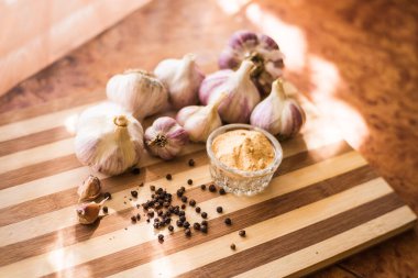 Kahverengi ahşap bir tahtanın üzerinde biber ve sarımsak çeşnili güzel ve büyük bir sarımsak var..