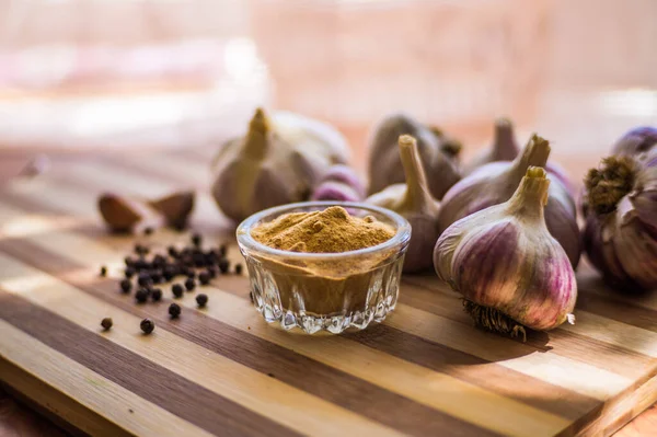 Kahverengi ahşap bir tahtanın üzerinde biber ve sarımsak çeşnili güzel ve büyük bir sarımsak var..