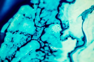 Mavi mürekkep beyaz lavaboya dökülmüş ve mürekkep soyut damlalar ve desenlere karışmış..