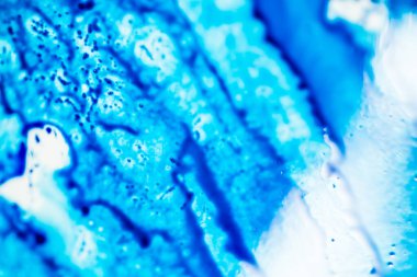 Mavi mürekkep beyaz lavaboya dökülmüş ve mürekkep soyut damlalar ve desenlere karışmış..