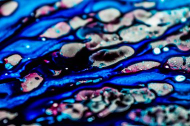 Mavi ve pembe mürekkep beyaz lavaboya dökülmüş ve mürekkep soyut damlalara ve desenlere karışmış..