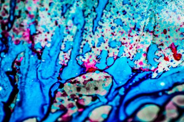 Mavi ve pembe mürekkep beyaz lavaboya dökülmüş ve mürekkep soyut damlalara ve desenlere karışmış..