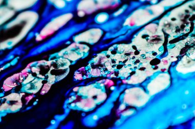 Mavi ve pembe mürekkep beyaz lavaboya dökülmüş ve mürekkep soyut damlalara ve desenlere karışmış..