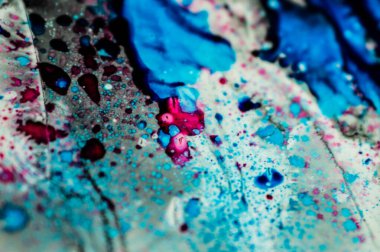 Mavi ve pembe mürekkep beyaz lavaboya dökülmüş ve mürekkep soyut damlalara ve desenlere karışmış..