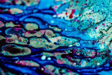 Mavi ve pembe mürekkep beyaz lavaboya dökülmüş ve mürekkep soyut damlalara ve desenlere karışmış..