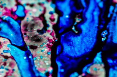 Mavi ve pembe mürekkep beyaz lavaboya dökülmüş ve mürekkep soyut damlalara ve desenlere karışmış..