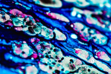 Mavi ve pembe mürekkep beyaz lavaboya dökülmüş ve mürekkep soyut damlalara ve desenlere karışmış..