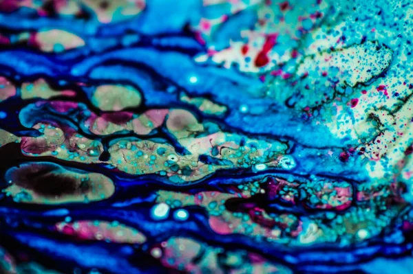 Mavi ve pembe mürekkep beyaz lavaboya dökülmüş ve mürekkep soyut damlalara ve desenlere karışmış..