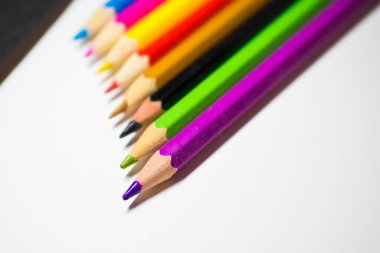 Çizim için renkli kalemler, iyice sivriltilmiş, beyaz arka planda sıralanmış..