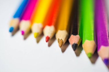 Çizim için renkli kalemler, iyice sivriltilmiş, beyaz arka planda sıralanmış..