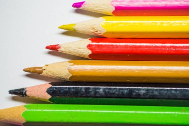 Çizim için renkli kalemler, iyice sivriltilmiş, beyaz arka planda sıralanmış..