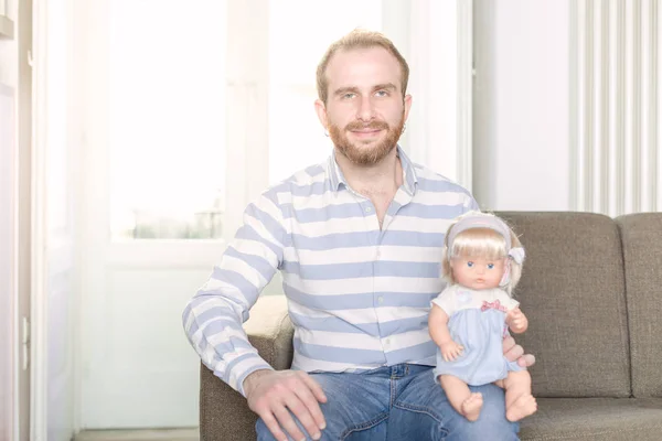 Homme Rousse Souriant Sur Canapé Avec Une Poupée Assise Sur Images De Stock Libres De Droits