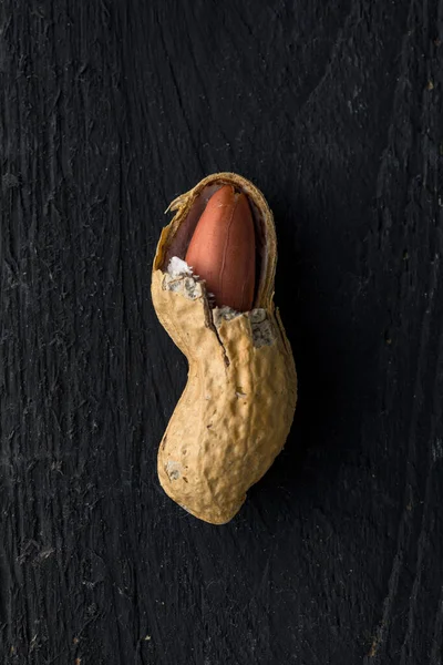 Geöffnete Erdnussschale Mit Einem Samen Darin Auf Einer Schwarzen Holzoberfläche — Stockfoto