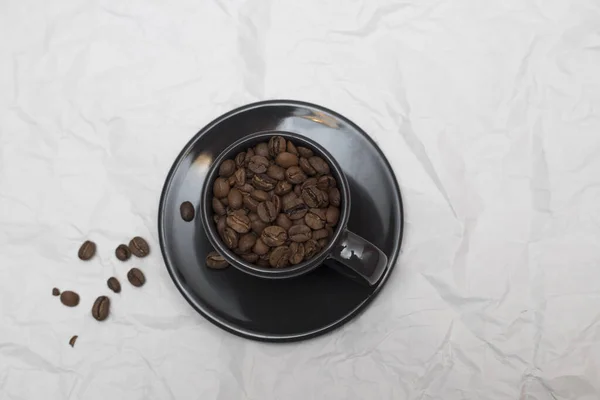 Granos de café en taza de café negro aislado en blanco — Foto de Stock