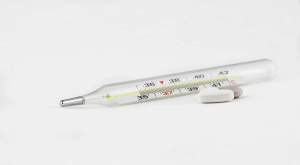 温度計や多くの錠剤が白い背景でクローズアップされています。風邪、インフルエンザ、季節、秋、冬、免疫 — ストック写真