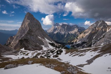 Panorama of lake Seebensee during spring with mountain peak Sonnenspitze and Zugspitze, dramatic clouds in sky, little snow, Ehrwald Austria clipart