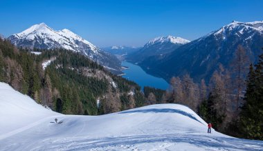 Achensee dağlarında kayak turu yapan bir adam, Baerenkopf 'un dağlık zirvesine dağ manzarasının önünde, bir tahtanın üzerinde tırmanan bir adam.
