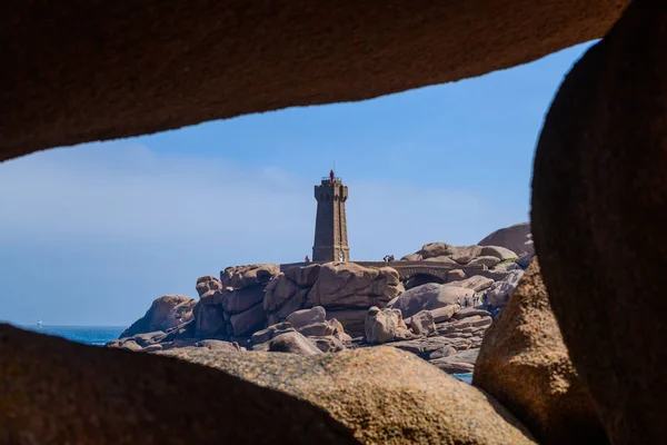 Zeegezicht met enorme roze granieten rotsblokken en een vuurtoren in de buurt van P — Stockfoto