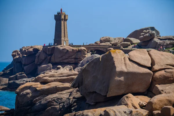 Zeegezicht met enorme roze granieten rotsblokken en een vuurtoren in de buurt van P — Stockfoto