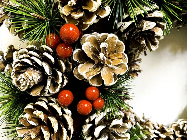 Christmas wreath with decorative berries and natural cones. Close up.