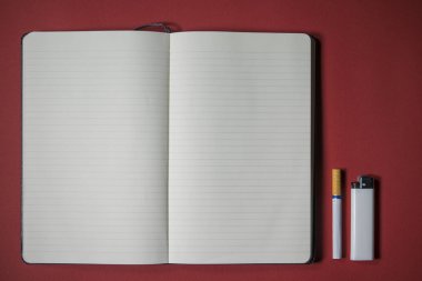 kırmızı arka plan üzerine sigara, çakmak ve dizüstü yazma