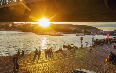 Günbatımı - Prag 'daki Vltava nehri boyunca oturan ve yürüyen insanlar - Çek Cumhuriyeti' nin başkentinde inanılmaz bir Temmuz. Parlak gün batımı ve Vltava 'da tekneler (tanınmayan kişi))