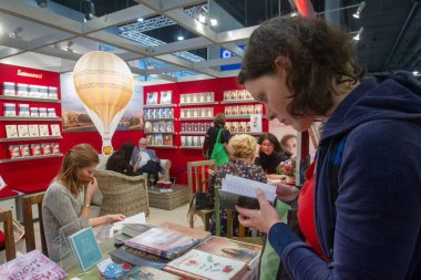 10 / 21 / 2016 Franfurk, Almanya. Franfurkt 'taki Kitap Fuarı' ndaki (içeride) insanlar. Genç bir kadın küçük bir kitap arıyor.