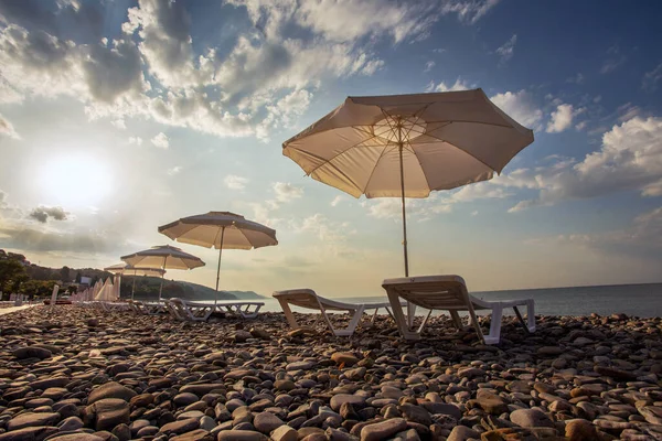 Büyük Soçi 'de Idyllic günbatımı (Lazarevskoe). Güneş tenteleri ve güneş yatakları çiftler halinde dizilmiş. Krasnodarskiy bölgesinin en iyi Rus güney tatil beldesi, Stalin zamanında 1938 'de Karadeniz' de, Kafkas Dağları 'na kapatıldı.