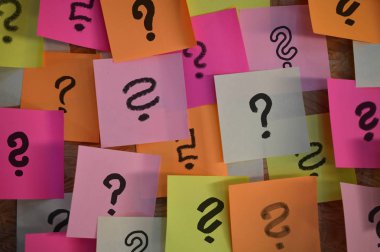Kırmızı, pembe, beyaz, sarı ve turuncu yapışkan notlar üzerinde el yazısı farklı soru işaretleri