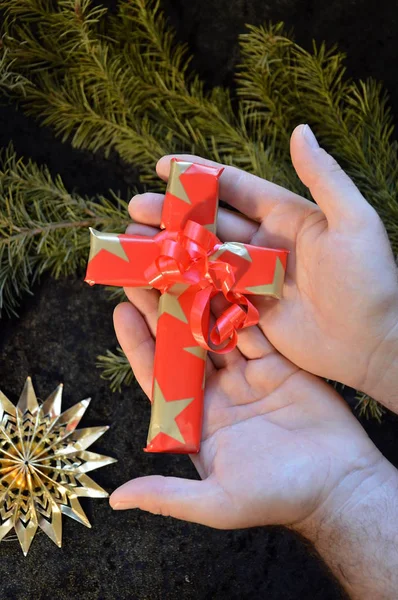 クリスマスの日にプレゼントとして紙に包まれたクロスを提供する手 — ストック写真