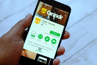 Bandar Seri Begawan, Brunei - 25 Temmuz 2018: Grindr uygulaması ile smartphone android Google oyun satan bir yerde tutan bir erkek el.