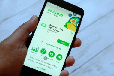 Bandar Seri Begawan, Brunei - 25 Temmuz 2018: Grabfood uygulaması ile smartphone android Google oyun satan bir yerde tutan bir erkek el.