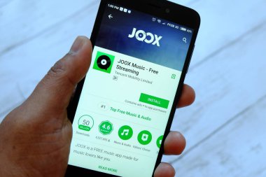 Bandar Seri Begawan, Brunei - 25 Temmuz 2018: Joox app ile akıllı telefon android Google oyun satan bir yerde tutan bir erkek el