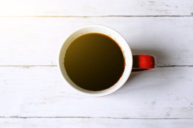 Beyaz ahşap zemin üzerinde güneş parlama ile kırmızı bir kupa kahve en iyi görünümü.