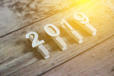 Yeni yıl 2019 kavramı. Clothpin güneş ile ahşap arka plan üzerindeki 2019 numarasıyla flare.
