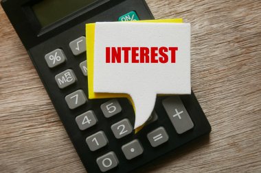 Tahta zeminde Faiz ile yazılmış hesap makinesi ve konuşma baloncukları.