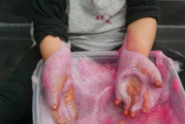 Kırmızı renkli sabun köpüğüyle oynayan çocukların seçici odak noktası.