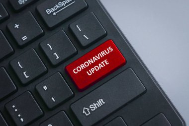 Covid-19 salgınının mevcut durumu için Coronavirus Güncellemesi ile birlikte kırmızı düğmeli siyah bir klavye.