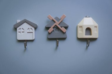 Gri arka planda anahtar sahibi bir evin çeşitli şekilleri. Mülkiyet, sigorta ve güvenlik kavramı.