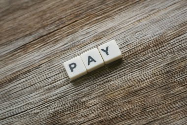 Tahta arka planda kare harften yapılmış ödeme sözcüğü.