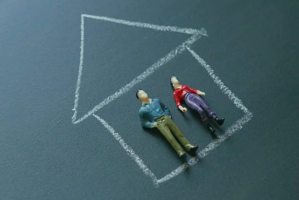 Miniature people on a chalkboard with drawing of a house. Concept of stay at home of coronavirus or covid-19 events.