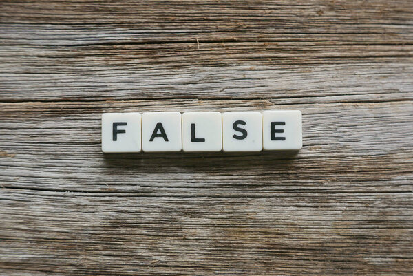 False word made of square letter word on wooden background.