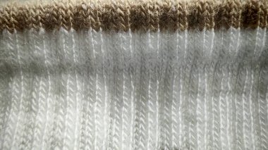 İki farklı bölümün farklı doku ve dikişlerini gösteren kahverengi kurdeleli beyaz bir çorabın ayrıntılı makro görüntüsü..