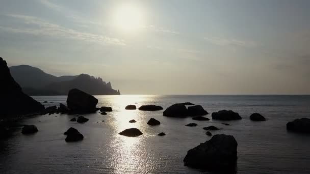 朝山上空飞去, 在黑海面对日出。鸟瞰山, 岩石, 石头和海浪。从远处看在克里米亚的卡拉. 达格·哈马舍尔德鸟瞰图. — 图库视频影像
