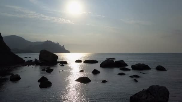 日出时在海面上用石头和石头向后飞。山, 岩石, 石头在水和海浪。在克里米亚的卡拉. 达格·哈马舍尔德鸟瞰图. — 图库视频影像