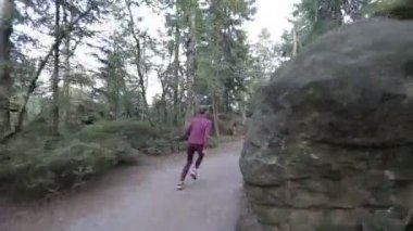 Genç kadın kayalar ve taşlar arasında bir turist geçiş yoluyla çalışır. Stabilize kamera ile izleme atış