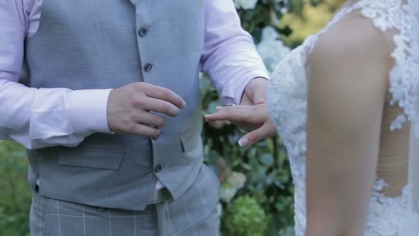Vőlegény hozza a Karikagyűrű menyasszony ujját. Közelkép a menyasszony és a vőlegény az esküvő gyűrű cseréje. Házasság, a kezet gyűrűk. — Stock videók